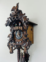 Wooden cuckoo clock with intricate details on a white wall