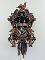 Wooden cuckoo clock with intricate design on a white background