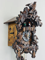 Wooden cuckoo clock with intricate carvings on a white background