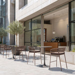 Outdoor seating area with tables and chairs in front of a modern building entrance.