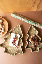 Two Christmas tree-shaped woven trays on a brown surface