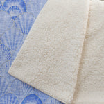 Close-up of textured beige fabric on a blue patterned background