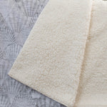 Close-up of a textured beige fabric on a patterned gray background