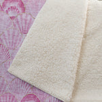 Close-up of a textured white rug on a pink floral-patterned surface