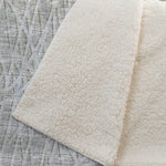Close-up of a textured beige rug on a textured gray surface