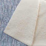 Close-up of textured beige fabric against a blue patterned background