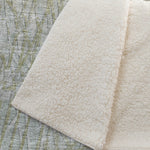 Close-up of textured beige fabric on a green and gray patterned surface