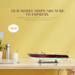 Model ship on a table with promotional text against a yellow wall