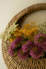 Woven basket with colorful flowers on a neutral background