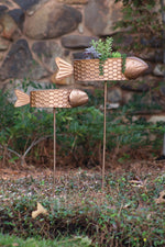 Decorative metal fish with a plant on a grassy area