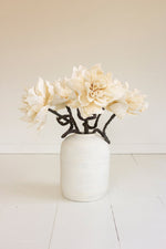 White vase with decorative black cat design and white flowers on a light background