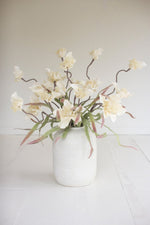 White vase with artificial flowers on a white surface