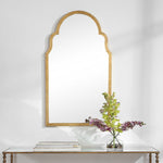 Decorative mirror with wooden frame on a white wall above a console table with a vase of flowers.