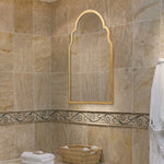 Bathroom with beige tiled walls, a decorative mirror, and towels.