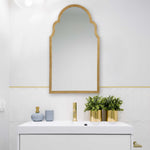 Bathroom vanity with gold-framed mirror, decorative vases, and plants.