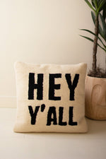 Beige pillow with 'HEY Y'ALL' text on a light background