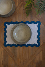 Set of ceramic plates on a wooden surface with a decorative placemat.