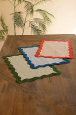 Three colorful placemats on a wooden table with a leafy background