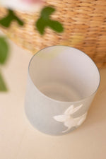 White ceramic cup with floral design on a beige surface