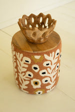 Decorative stool with floral pattern and wooden top on a light background