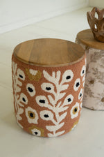 Round wooden stool with floral patterned fabric cover on a white surface