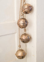 Decorative brass bells hanging on a white wall