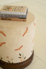Upholstered ottoman with embroidery and carved base
