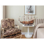Decorative chair with a model ship on a small table in a room.