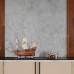 Model ship on a countertop with a textured wall background