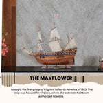Model of the Mayflower ship on a wooden shelf with a gray wall background