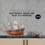 Model ship on a shelf with promotional text against a gray wall.