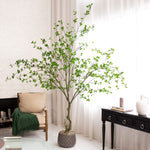 Decorative potted tree in a living room setting with a chair and table.