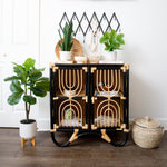Black and gold side table with decorative items and plants in a room.