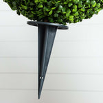 Black wall-mounted plant holder with a green potted plant on a white wall background