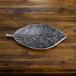 Metal leaf-shaped object on a wooden surface