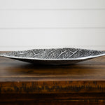 Decorative silver leaf-patterned bowl on a wooden surface with a white background