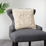 Gray chair with a textured beige pillow against a white paneled wall.