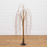 Artificial willow tree with a metallic finish on a wooden floor against a white wall.