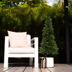 White chair with a beige pillow on a wooden deck surrounded by greenery