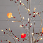 White decorative twig tree with glowing red and pink heart lights.