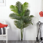 Artificial palm plant in a living room setting with a white wall and decorative items.