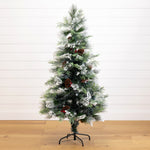 A pre-lit artificial Christmas tree with a flocked white finish, decorated with brown pinecones, standing on a black metal stand against a white shiplap wall and light wood floor.