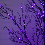 Purple LED branch lights strung along bare black decorative branches against a purple-lit background.