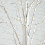 White birch tree artificial branch decoration with thin silver wire lights and small warm yellow bulbs, shown against a light gray background.