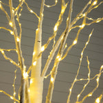 Warm white LED tree lights wrapped on a decorative branch structure against a gray paneled background.