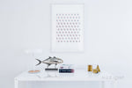 Decorative wall art with circular patterns on a white wall, featuring a fish sculpture and books on a table.