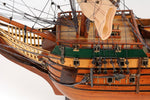 Close-up of a wooden model ship with detailed rigging on a white background