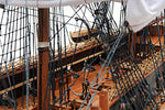 Close-up of a model ship's interior with ropes and wooden planks.