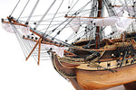 Close-up of a model ship with detailed rigging and wooden structure on a white background