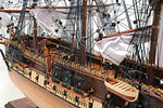 Detailed model of a ship with masts, rigging, and flags on a white background